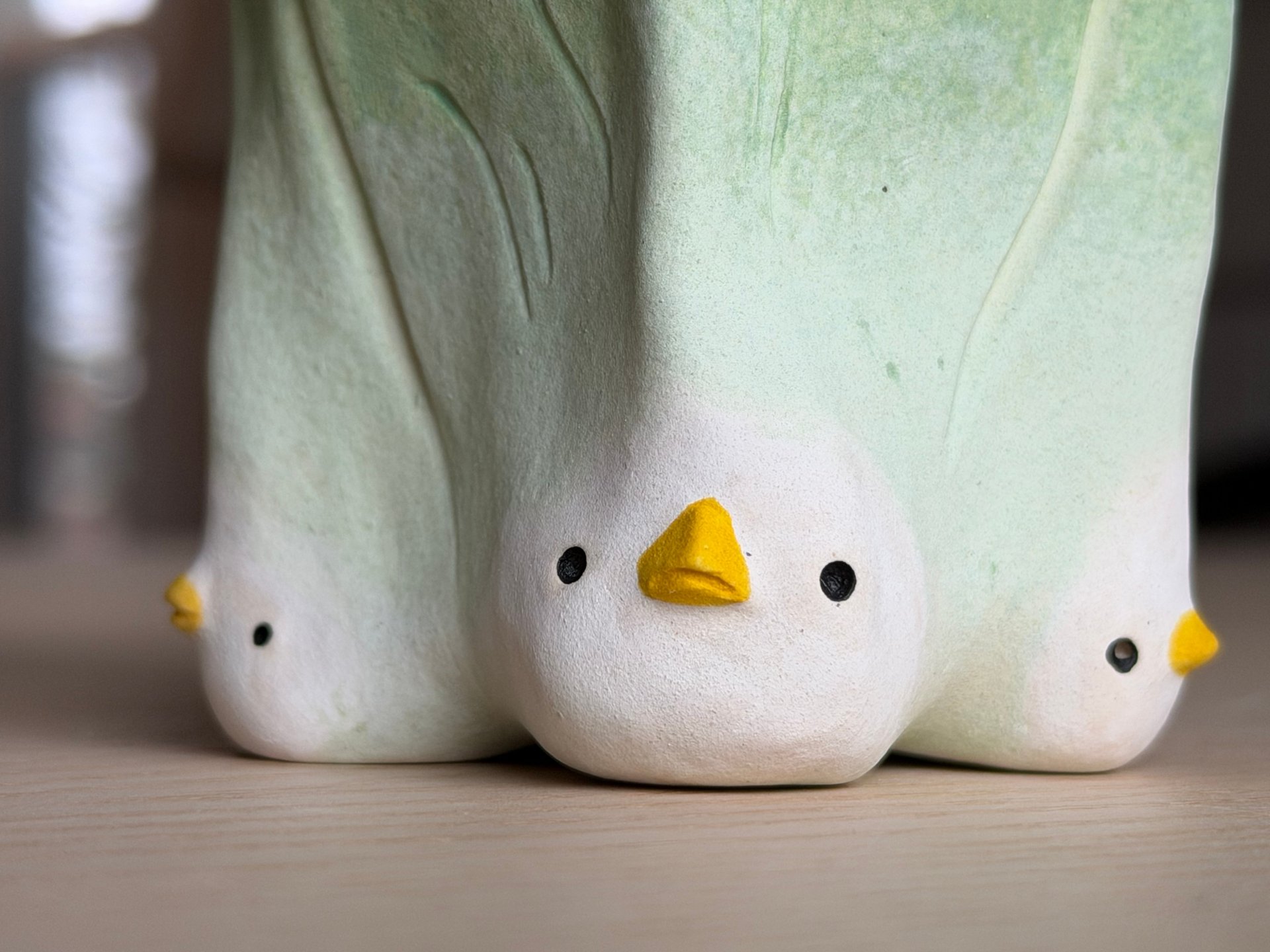 Three little chicken heads with yellow beaks tucked along the base