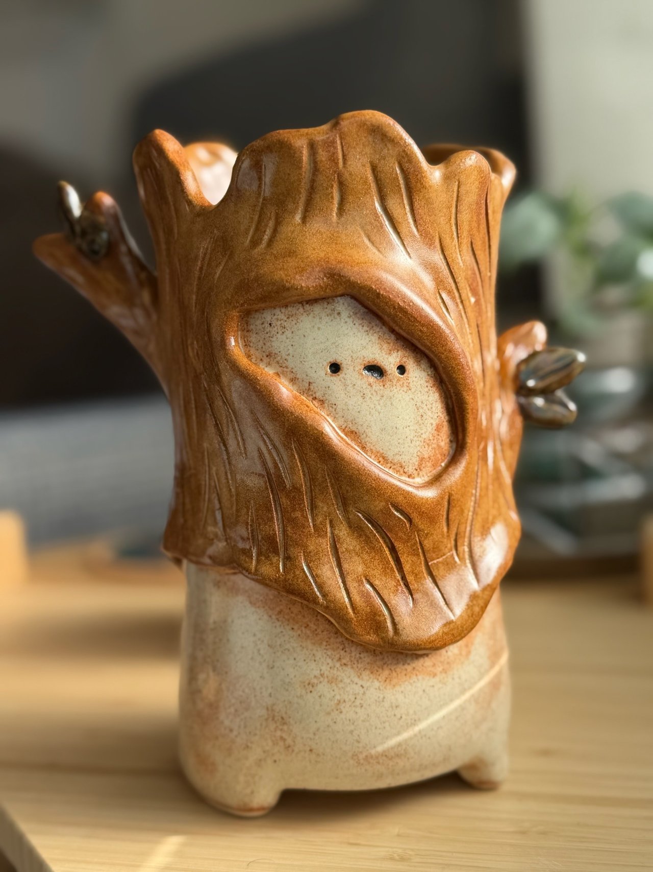 A pale speckled sprite peering out of a hollow honey-glazed log, its face framed by carved bark