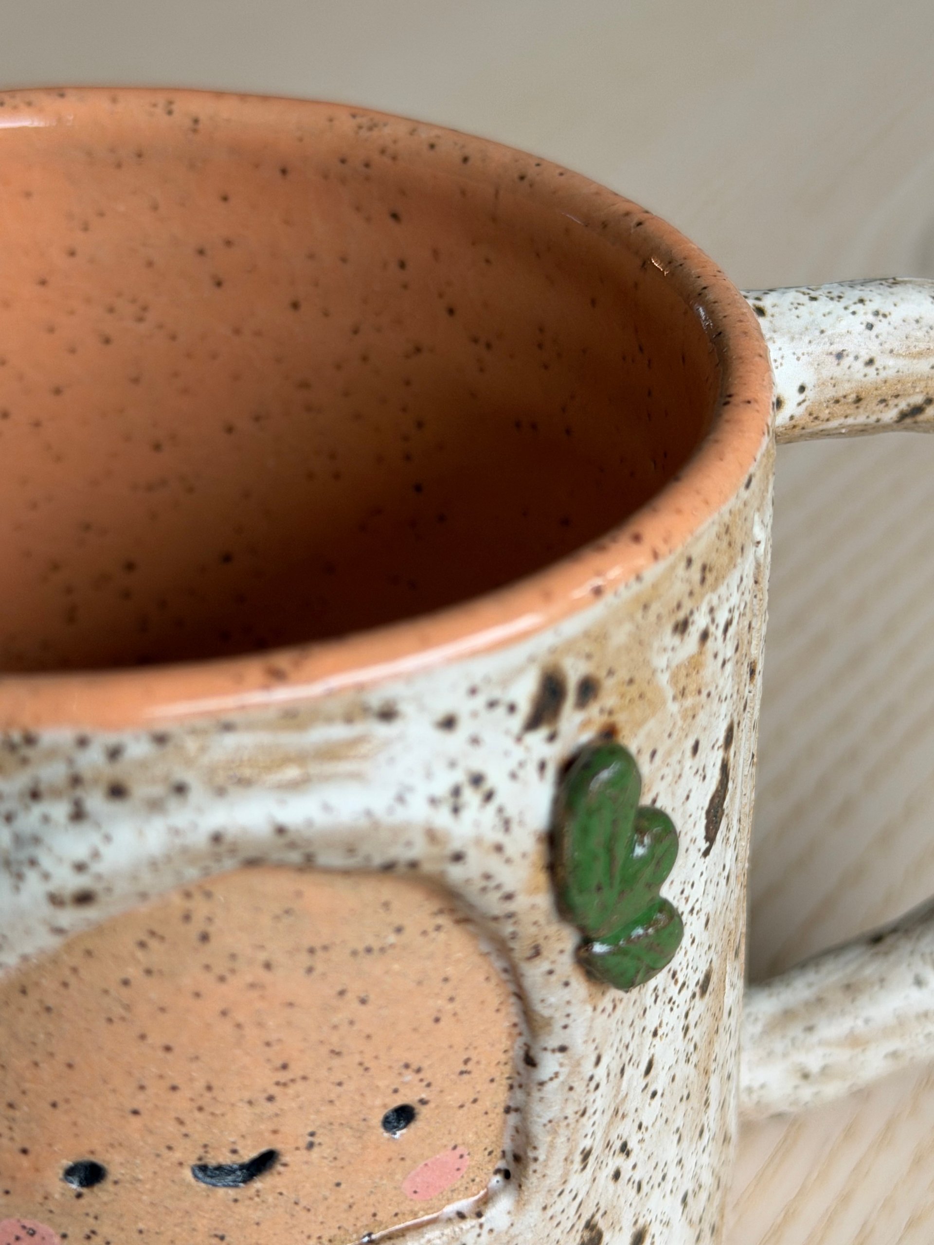 The pale mug's peach interior above its smiling face